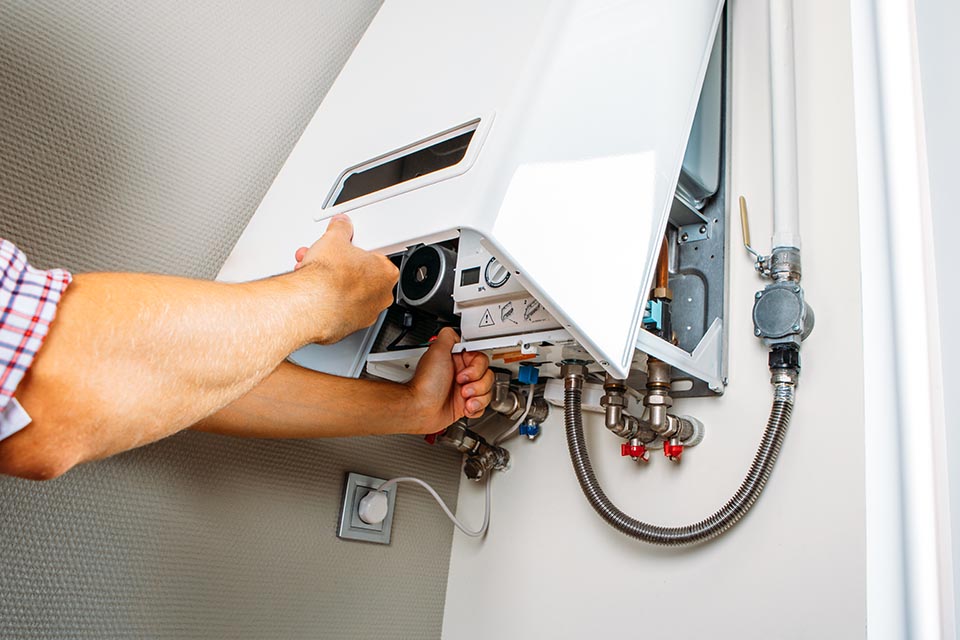 Technician connecting gas and water supply to a tankless water heater unit