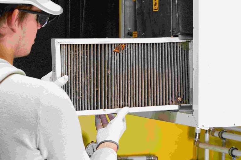 Technician replacing a dirty air filter in a central ventilation system